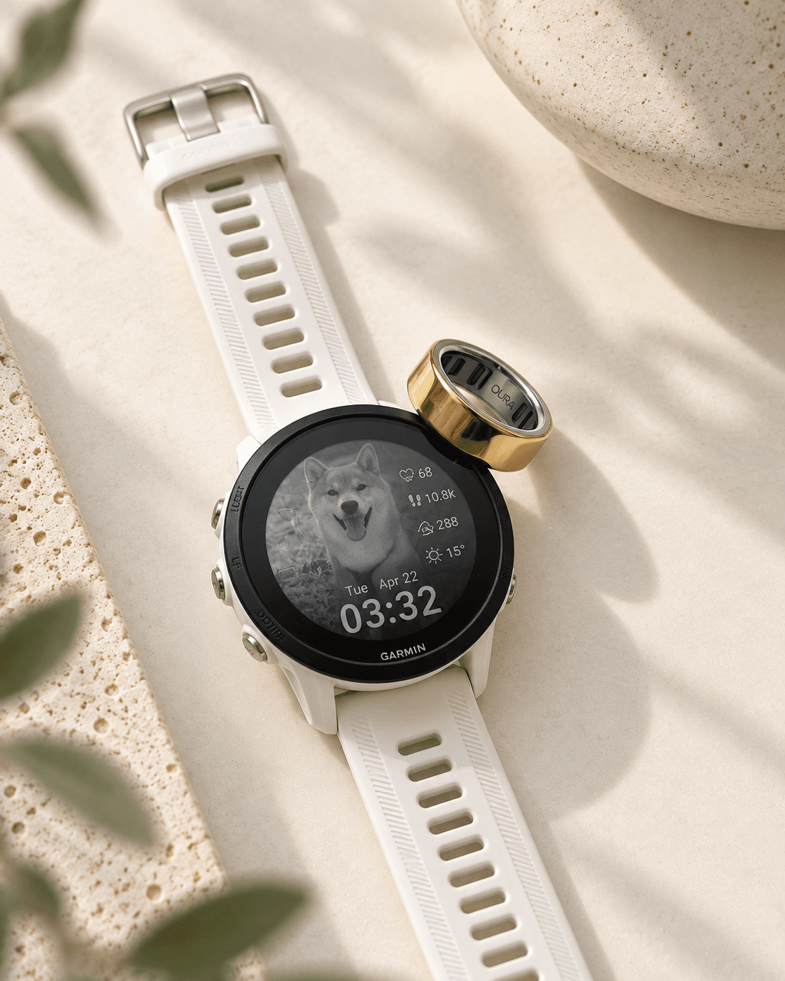 A Garmin watch and Oura ring on a cream surface